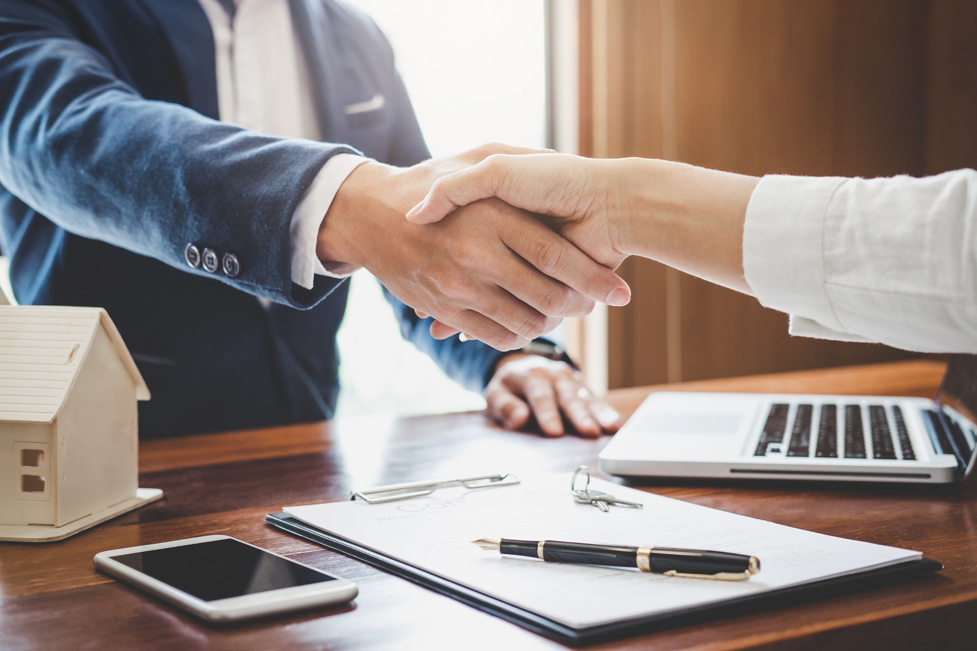 Real estate agent and customers shaking hands together celebrating finished contract after about home insurance and investment loan, handshake and successful deal